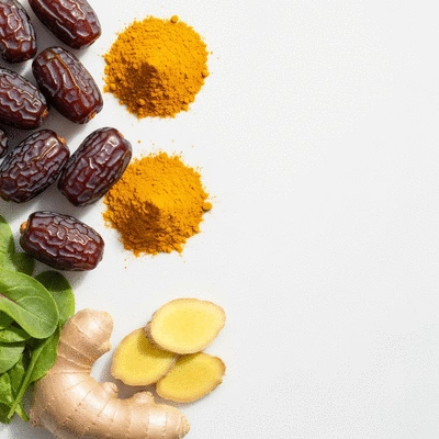 Assortment of anti-inflammatory foods, including dates, turmeric, ginger, and leafy greens, arranged artfully on a light background, no text, no words, no typography, clean image