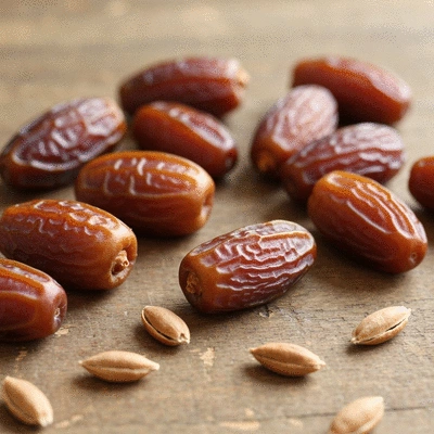 Close-up of fresh dates on a rustic wooden table, emphasizing their natural sweetness and texture, surrounded by scattered date pits.