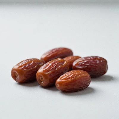 A close-up of several dates on a clean, light surface, suggesting healthy snacking